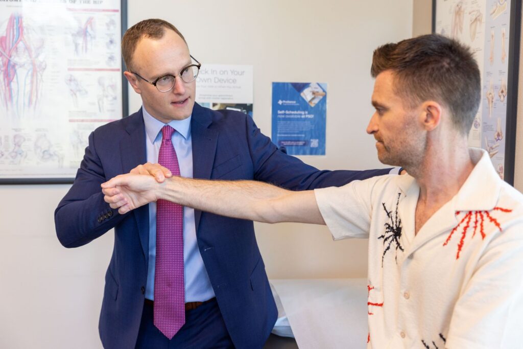 Orthopedic provider checking a patient's shoulder range of motion during an exam at Proliance Puget Sound Orthopaedics