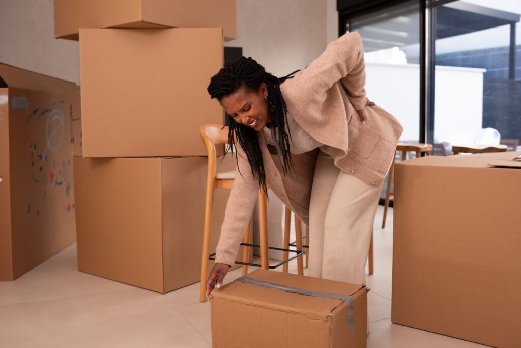 Woman straining her back while lifting a moving box