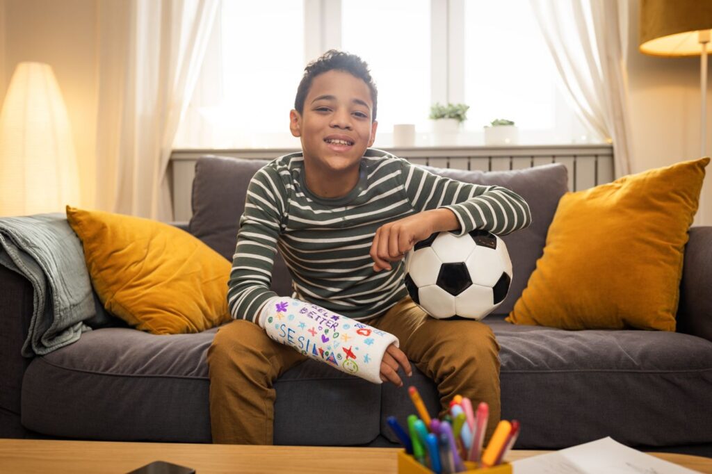 Young soccer player smiling with a decorated arm cast